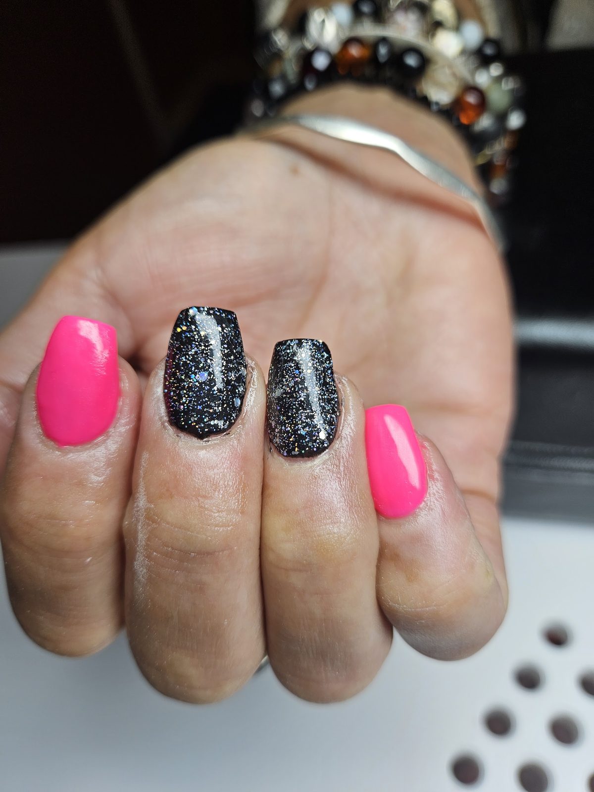 Knalroze en zwarte glitternagels in een lange, spitse vorm
