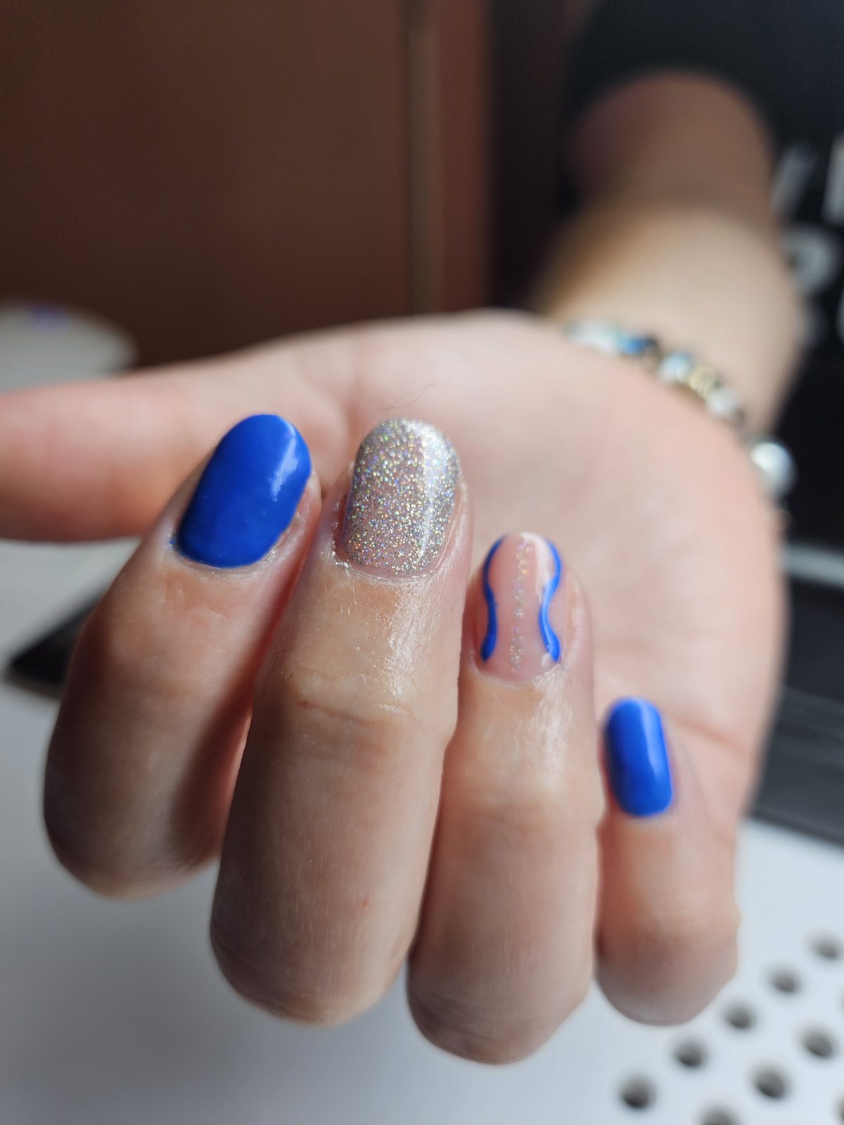 Kobaltblauwe nagels met zilverglitter en een golvend lijntje als nail-art